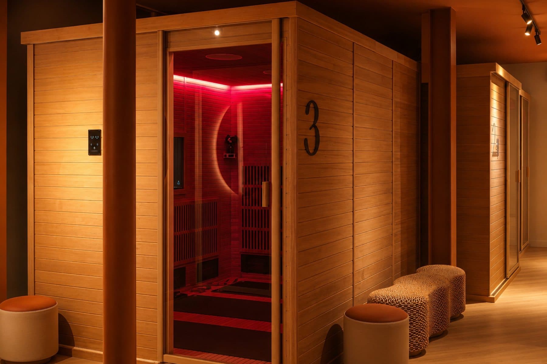 Une cabine Spark en bois clair, porte ouverte sur la lumière rouge de la séance